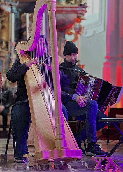 Bild mit Harfensolisin und Steirischer Harmonika solist in stimmungsvoller Atmosphäre in der Kirche