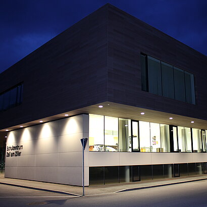 Aussenaufnahme des Schulgebäudes bei Dämmerung mit beleuchteter Fassade