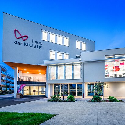 Aussenansicht des modernen Haus der Musik in Dämmerung mit beleuchteten Fenstern