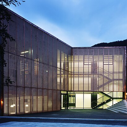 Aussenaufnahme der modernen Fassade der Landesmusikschule Landeck bei Dämmerung mit beleuchteten Fenstern