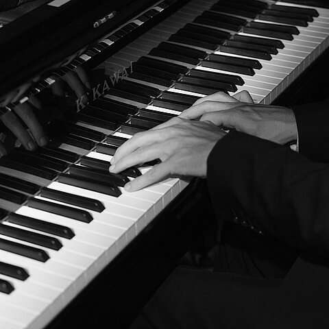 Klaviertasten mit spielenden Händen