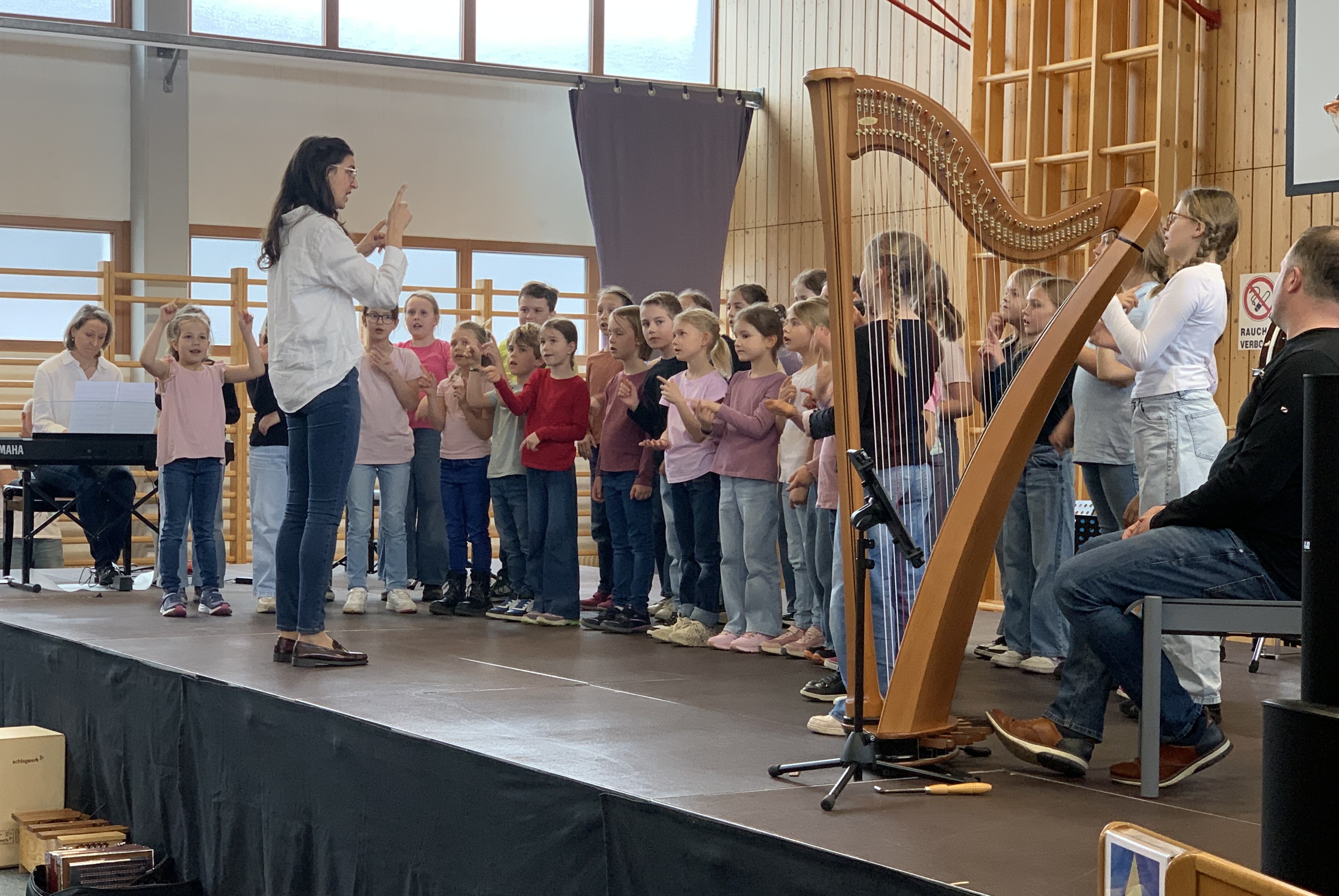 Kinderchor auf der Bühne, im Vordergrund steht auch eine Harfe